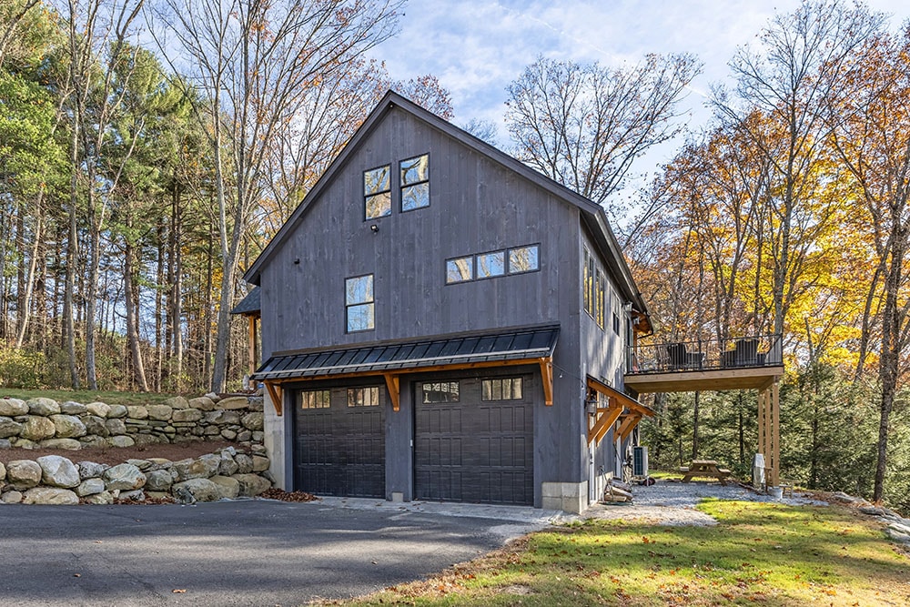 Modern garage with wooden awning and dark siding