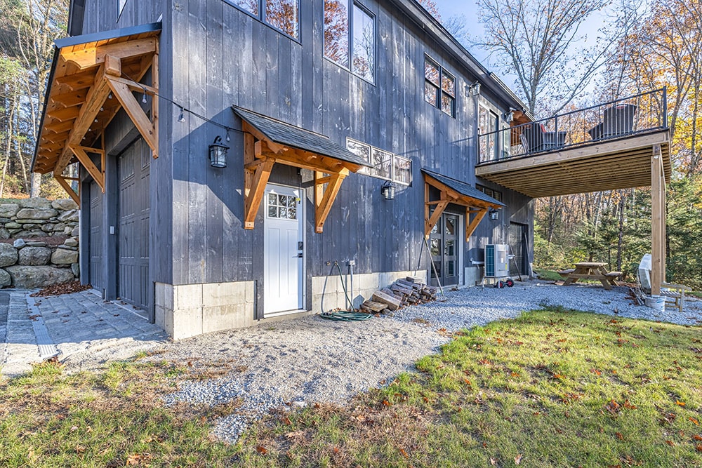 Modern garage with wooden awning and dark siding