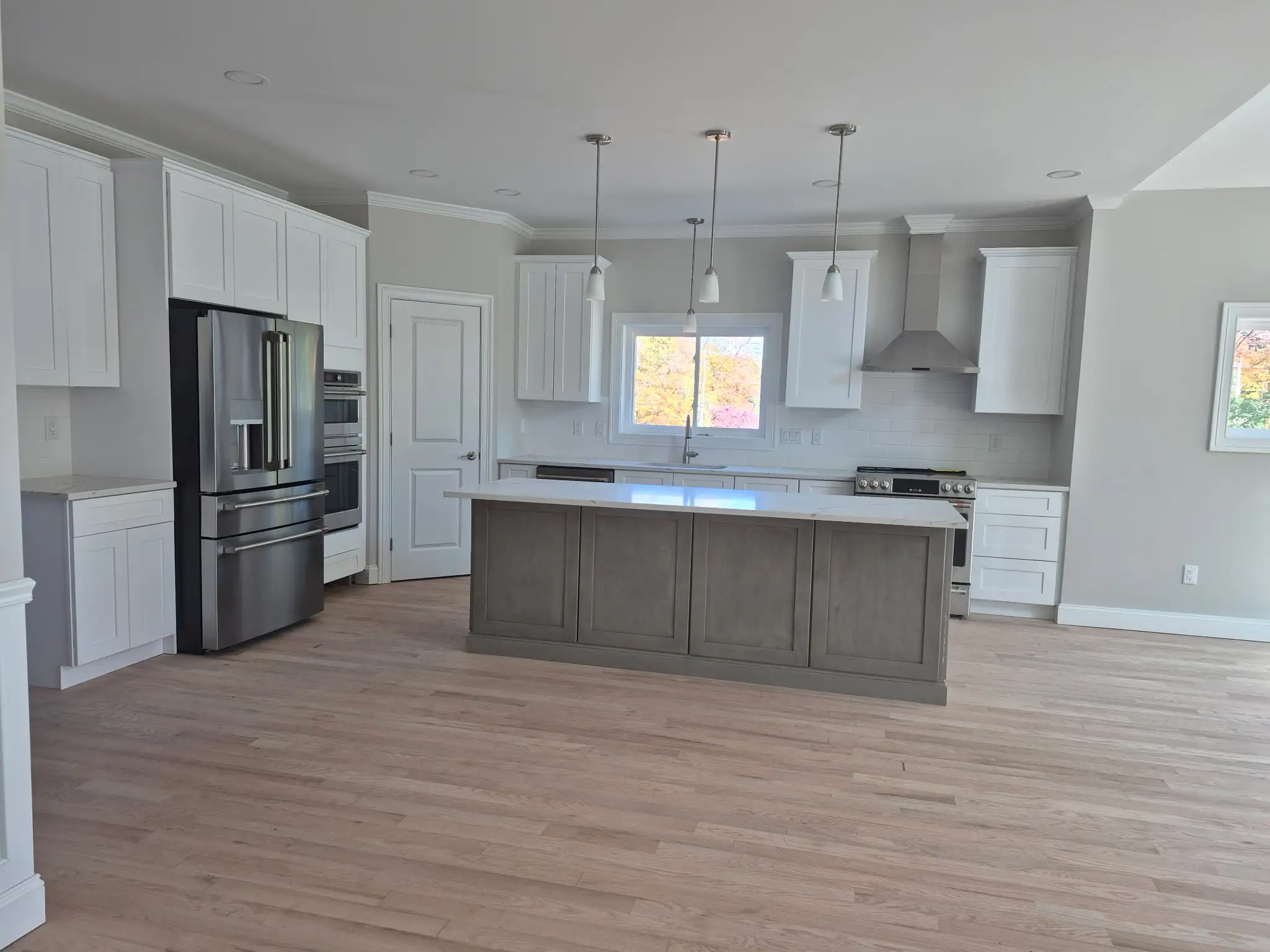 Bright kitchen with white cabinetry, center island, pendant lighting and stainless steel appliances