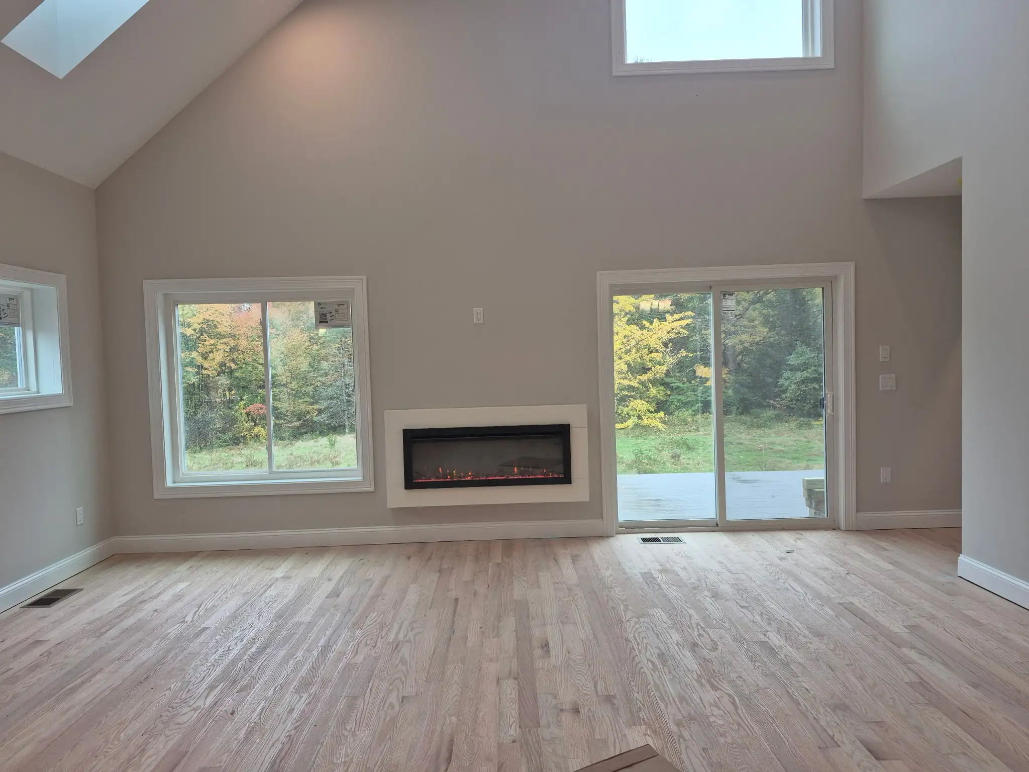 Two-story living room with vaulted ceiling, large windows and modern built-in fireplace