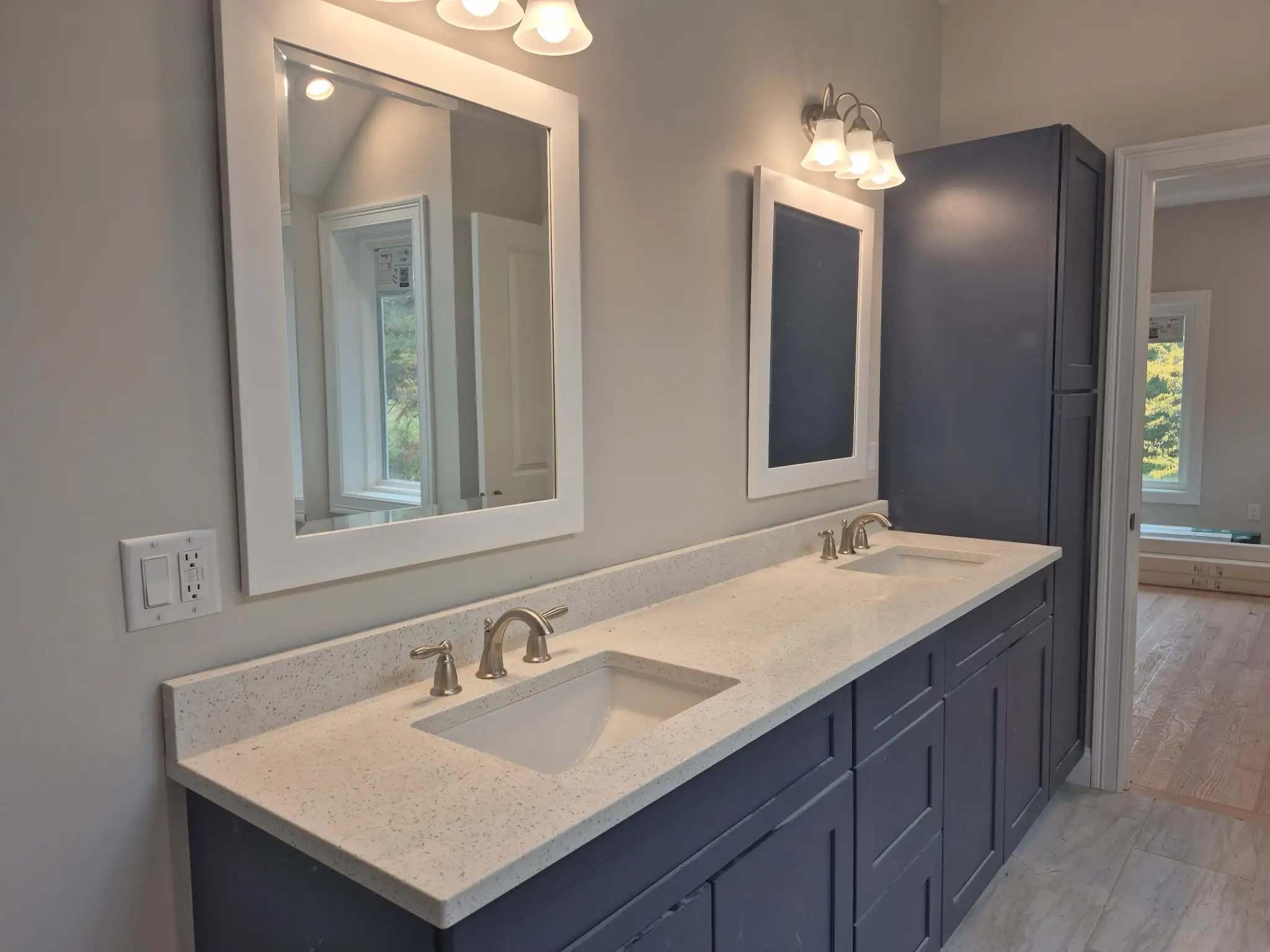 Modern bathroom with double-sink vanity, framed mirrors, granite countertop and wall-mounted lighting