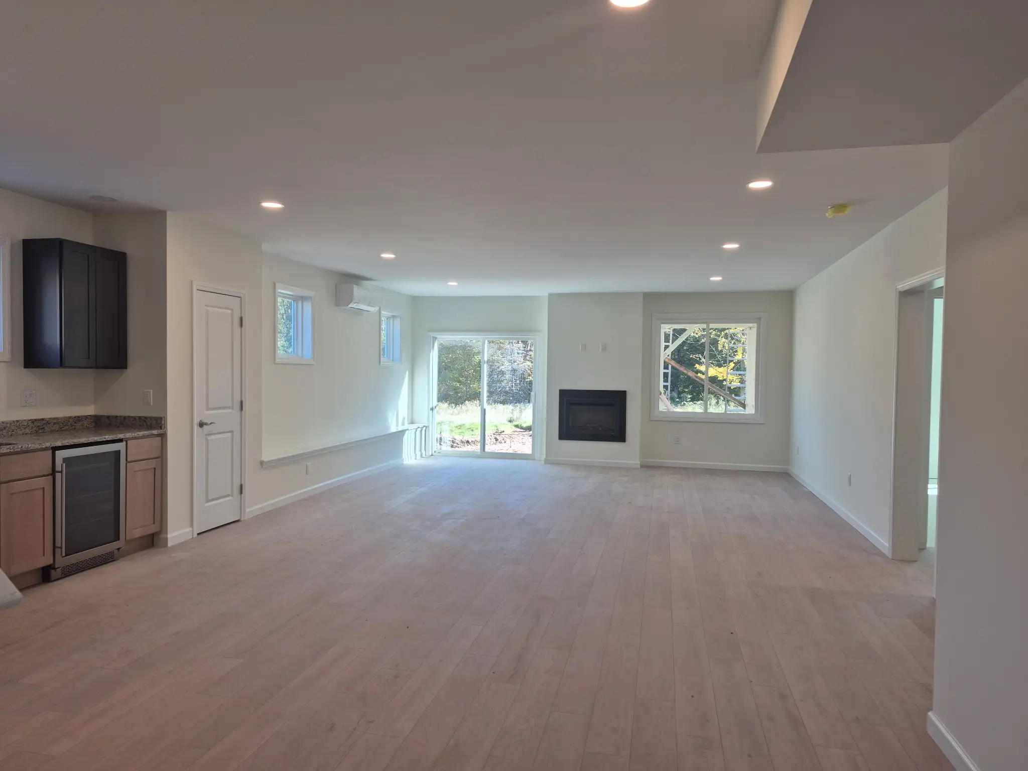 Spacious living room with recessed ceiling lights, modern fireplace and large glass patio doors