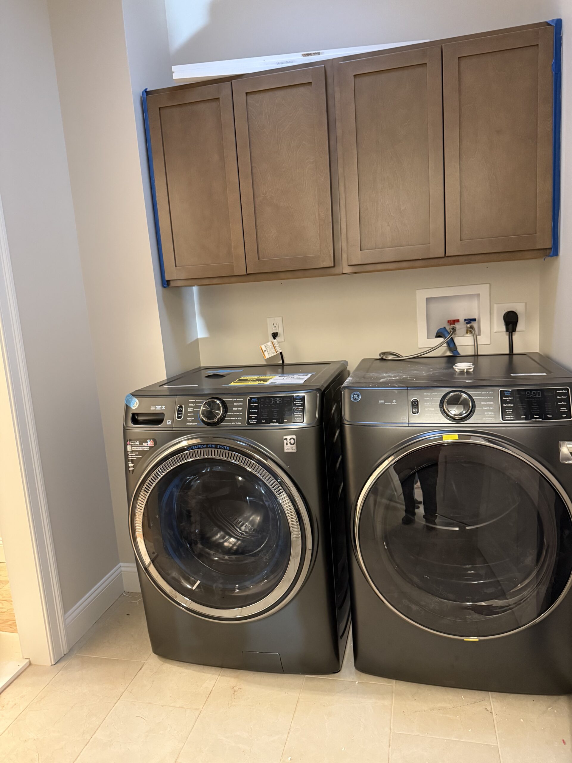 Laundry room with side-by-side washer and dryer, wooden overhead cabinets and countertop