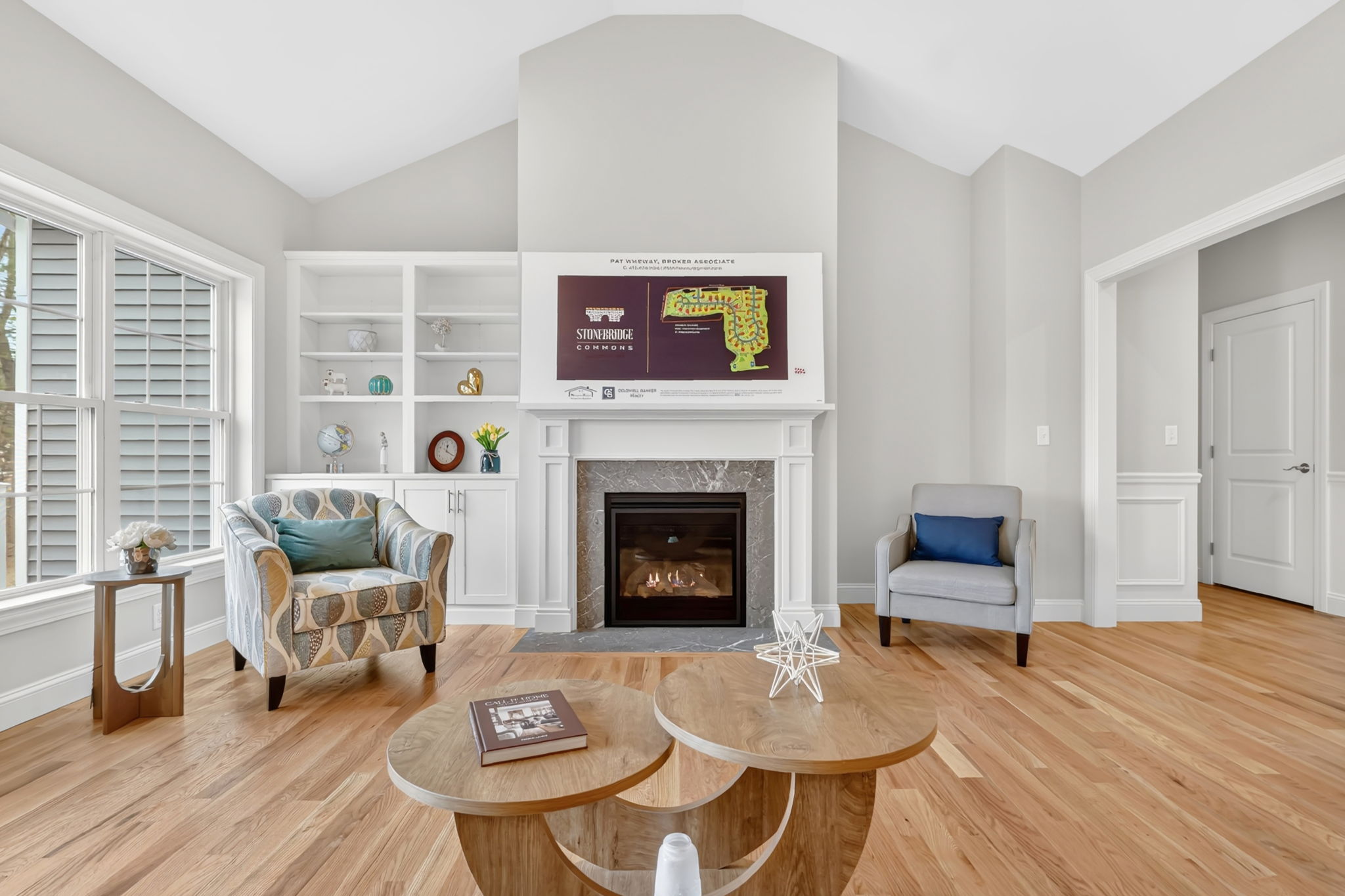 Bright living room with vaulted ceiling, hardwood floors, built-in shelves and fireplace