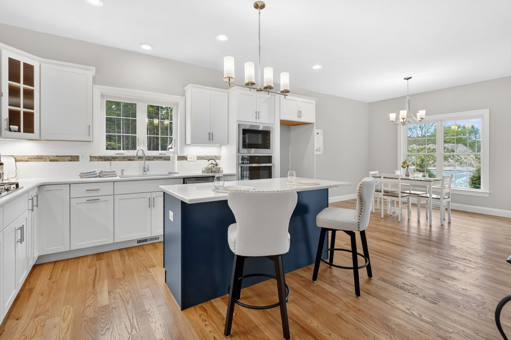 Modern white kitchen with navy blue island, pendant lighting and adjacent dining area