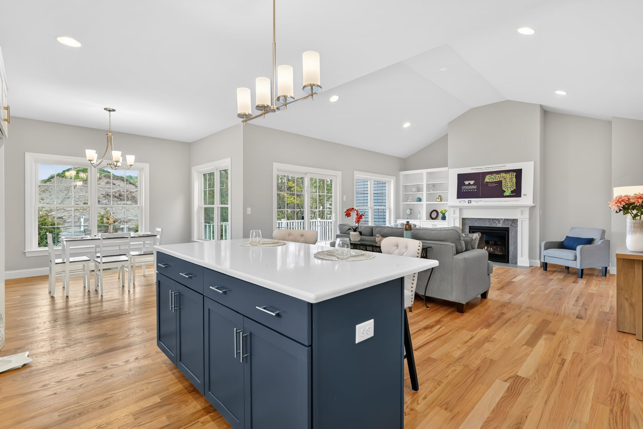 Open-concept kitchen and living area featuring navy blue island and vaulted ceiling