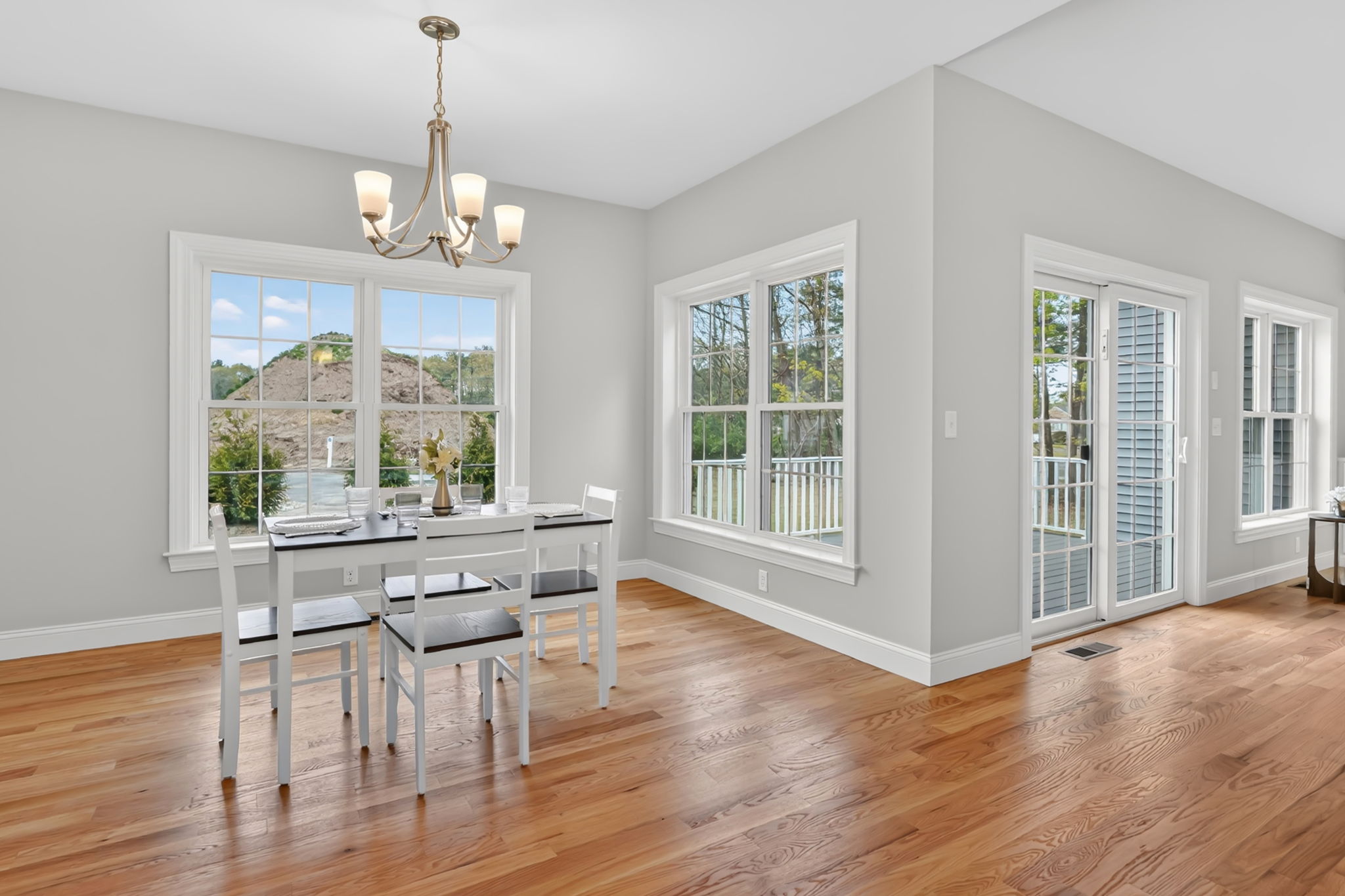 Bright dining area with hardwood flooring, chandelier, large windows and glass doors
