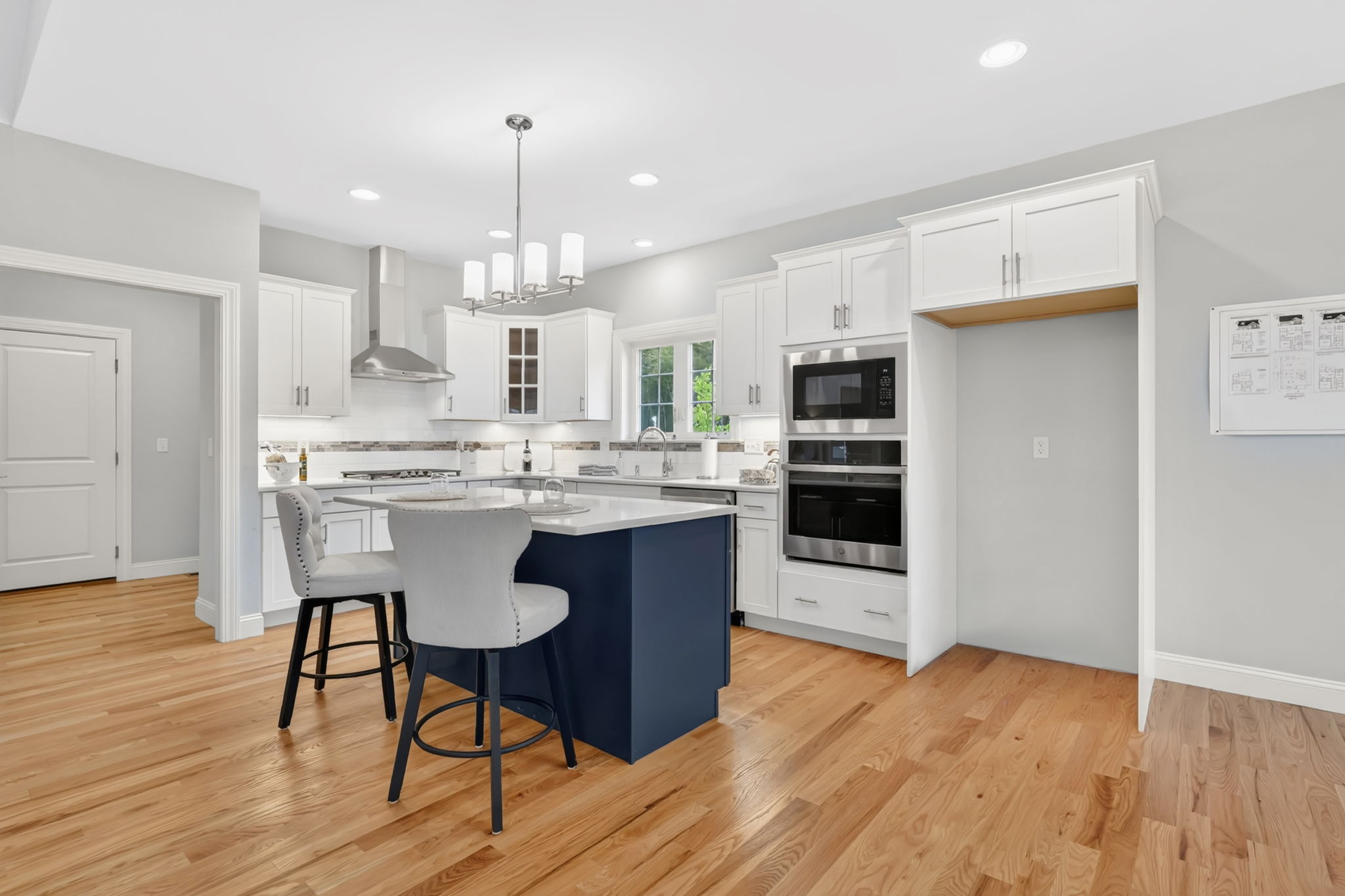 Spacious kitchen with navy blue center island, white cabinets and built-in double ovens