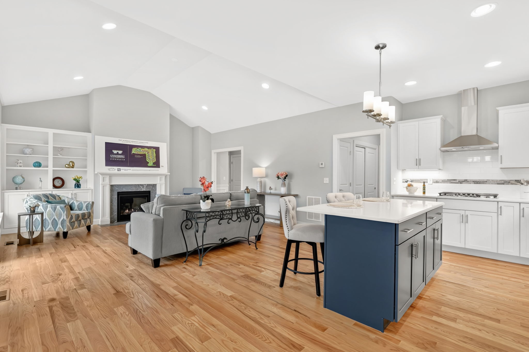 Open-concept living room and kitchen with hardwood floors, fireplace and center island