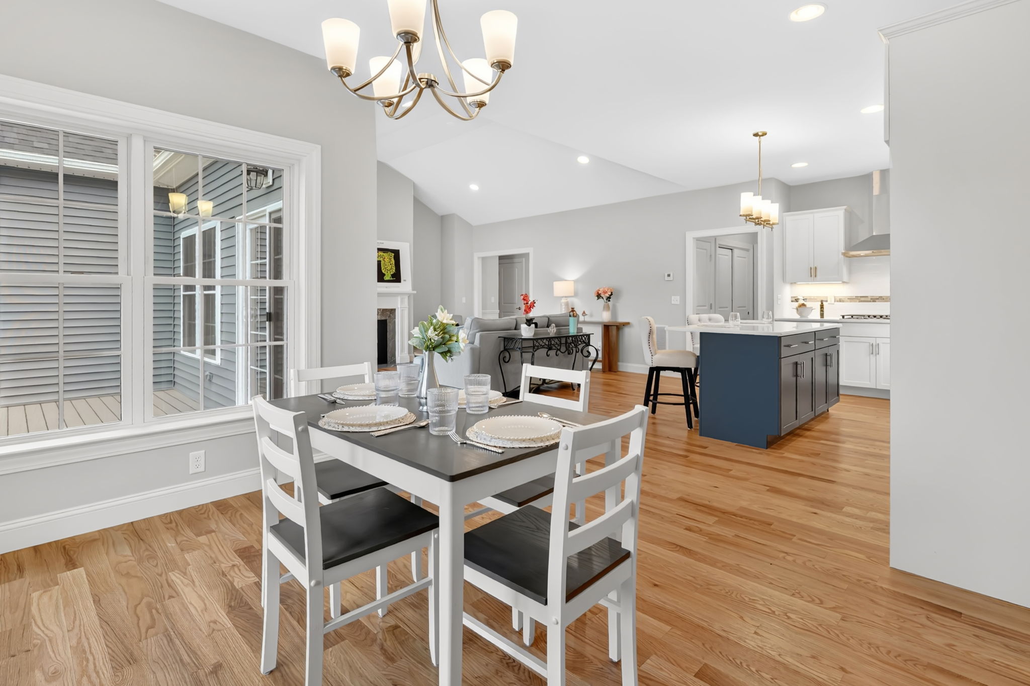 Dining area with white table and chairs overlooking an open-concept kitchen and living room