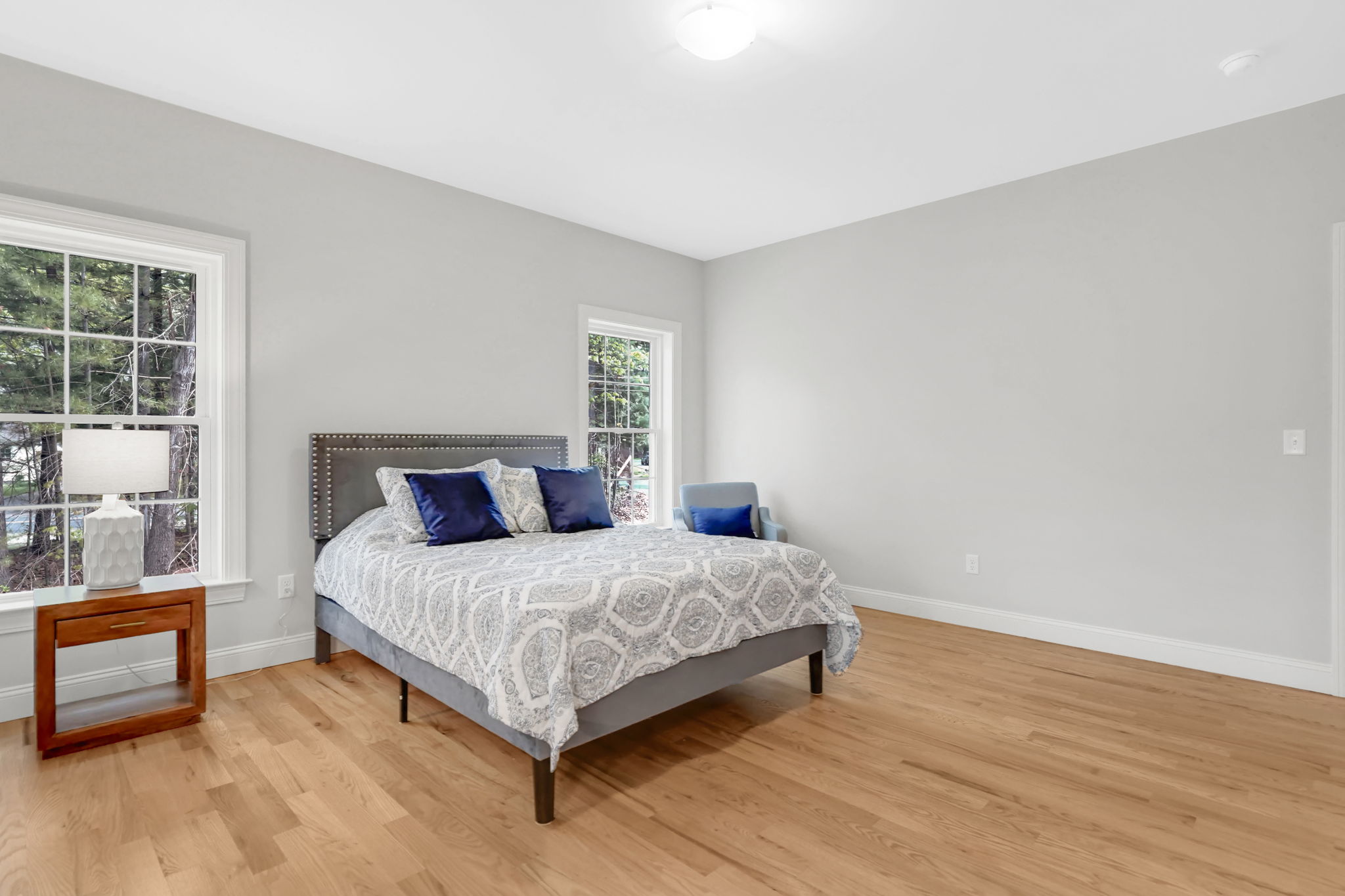 Spacious bedroom with patterned bedding, blue accent pillows and hardwood flooring