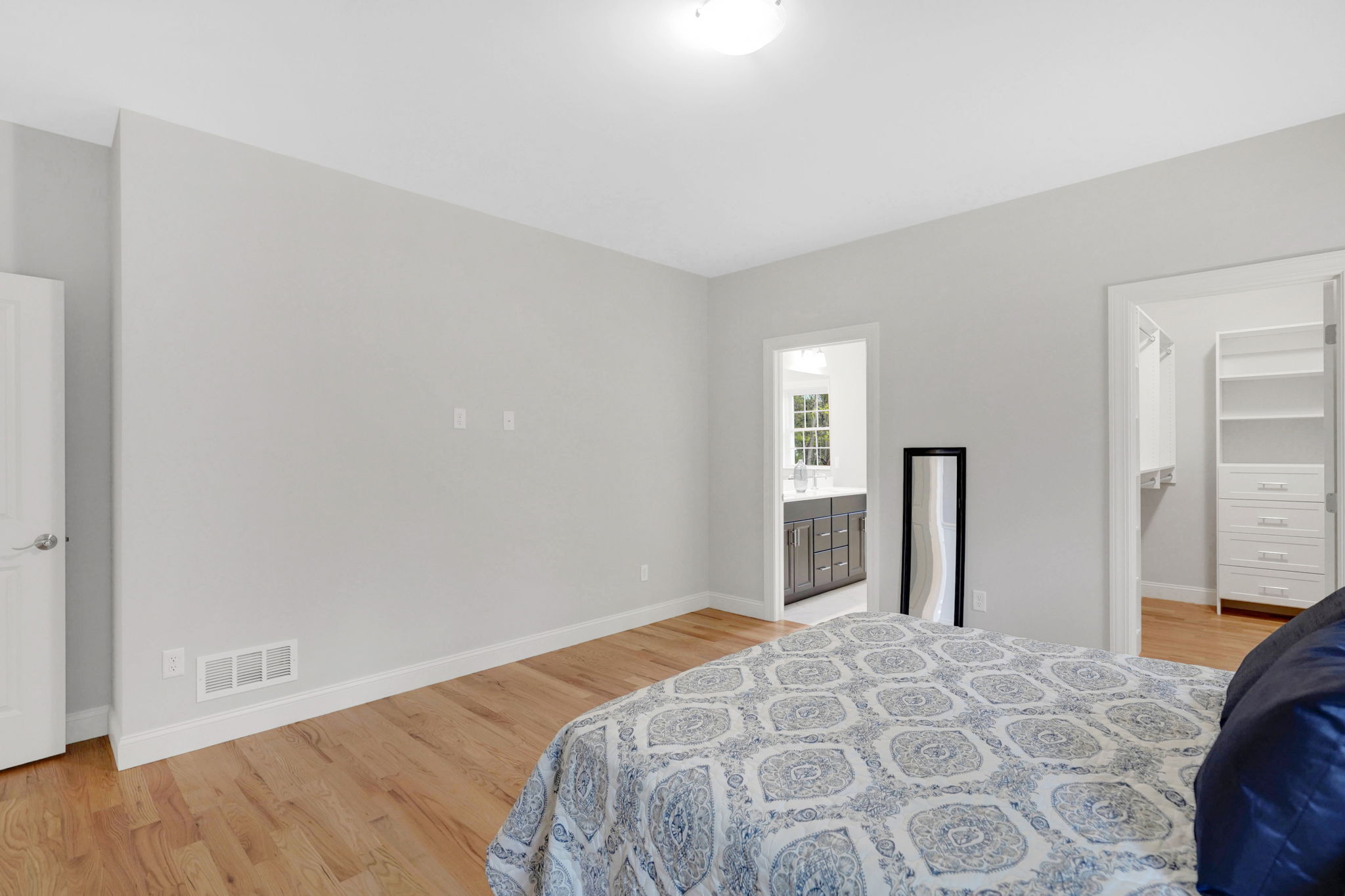 Bedroom with neutral gray walls, hardwood flooring and doorway leading to a walk-in closet
