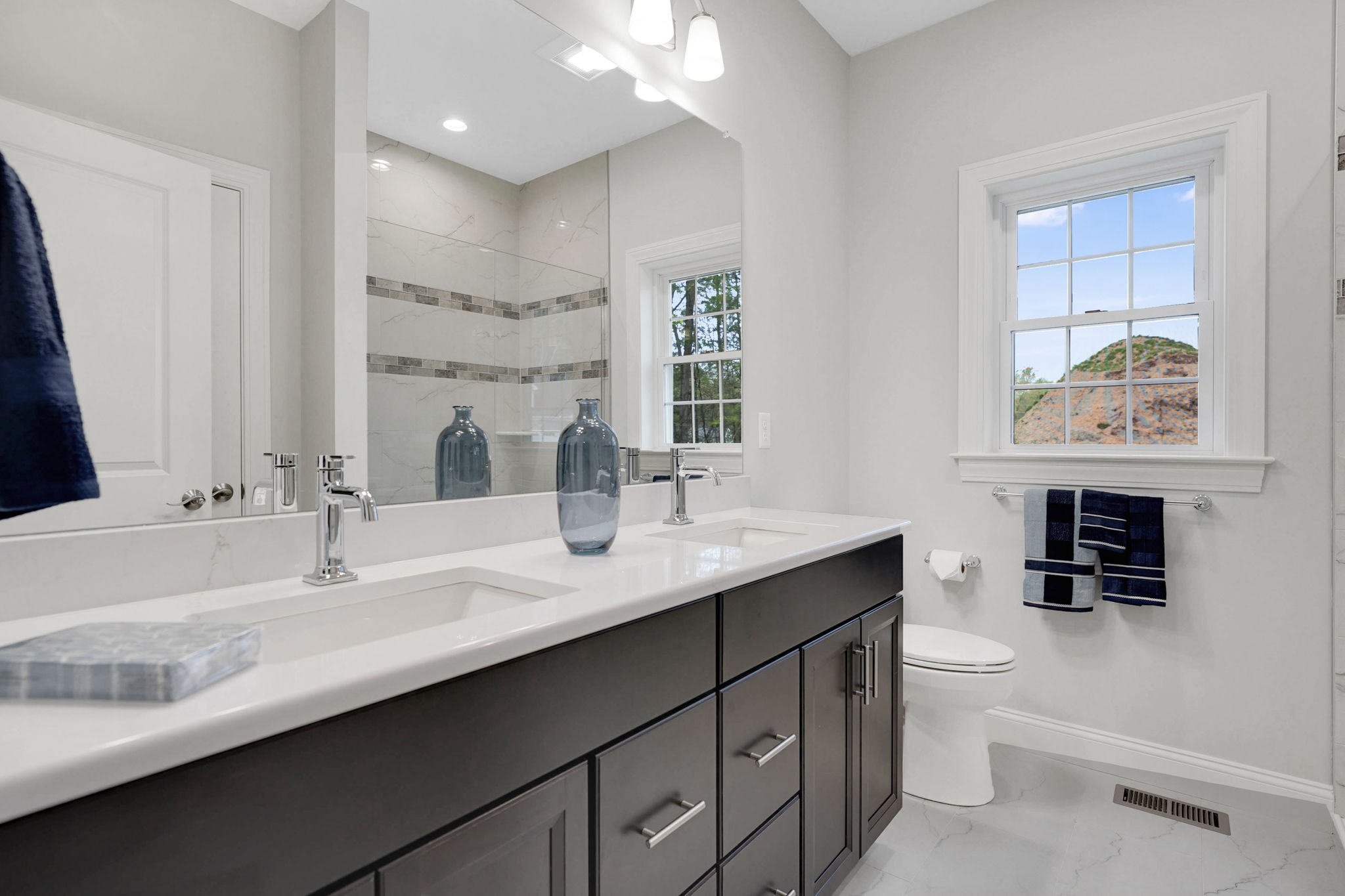Modern bathroom with double-sink vanity, dark cabinets, large mirror and tiled backsplash