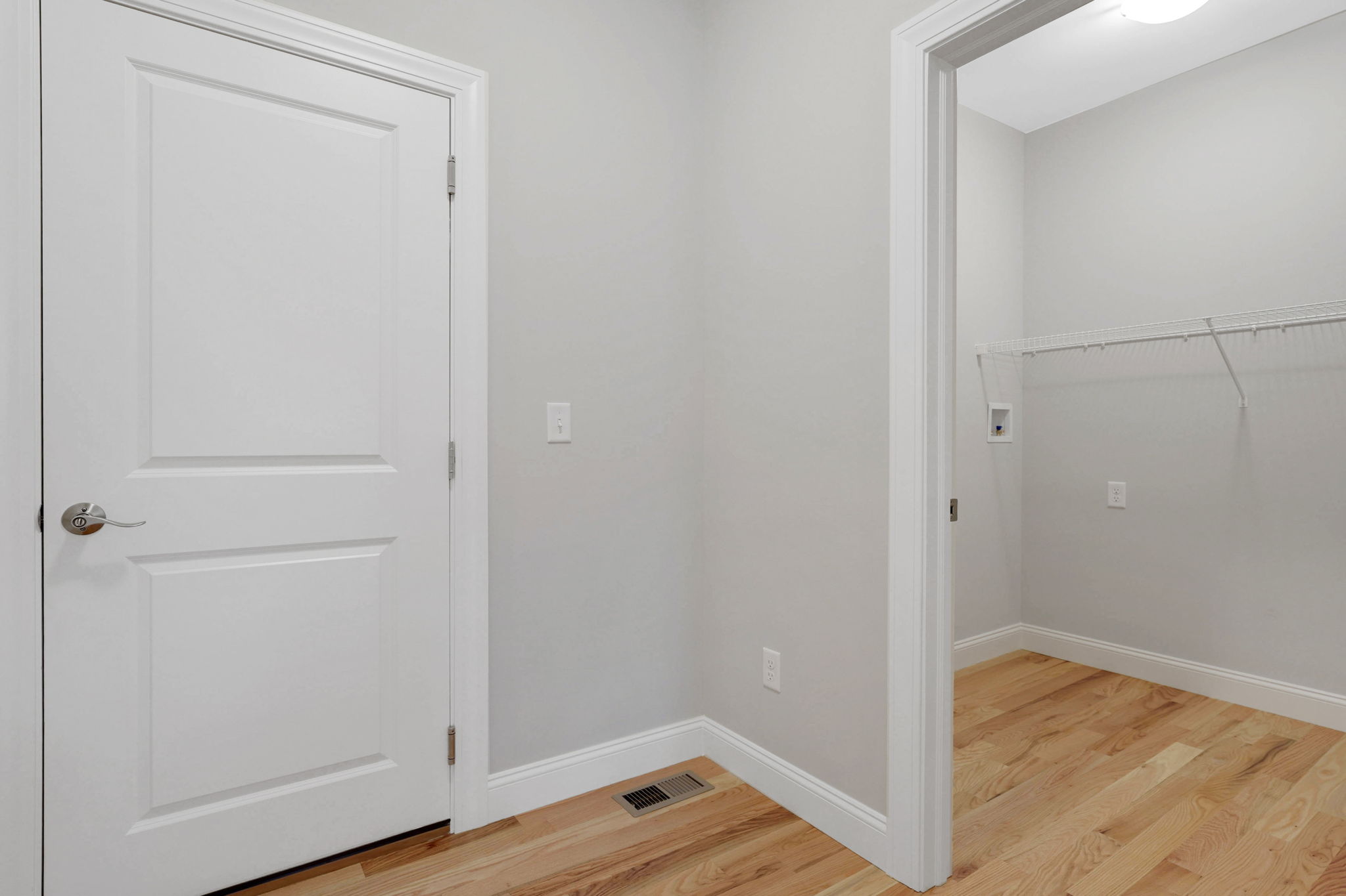 Interior hallway with white doors, hardwood flooring and adjacent walk-in closet