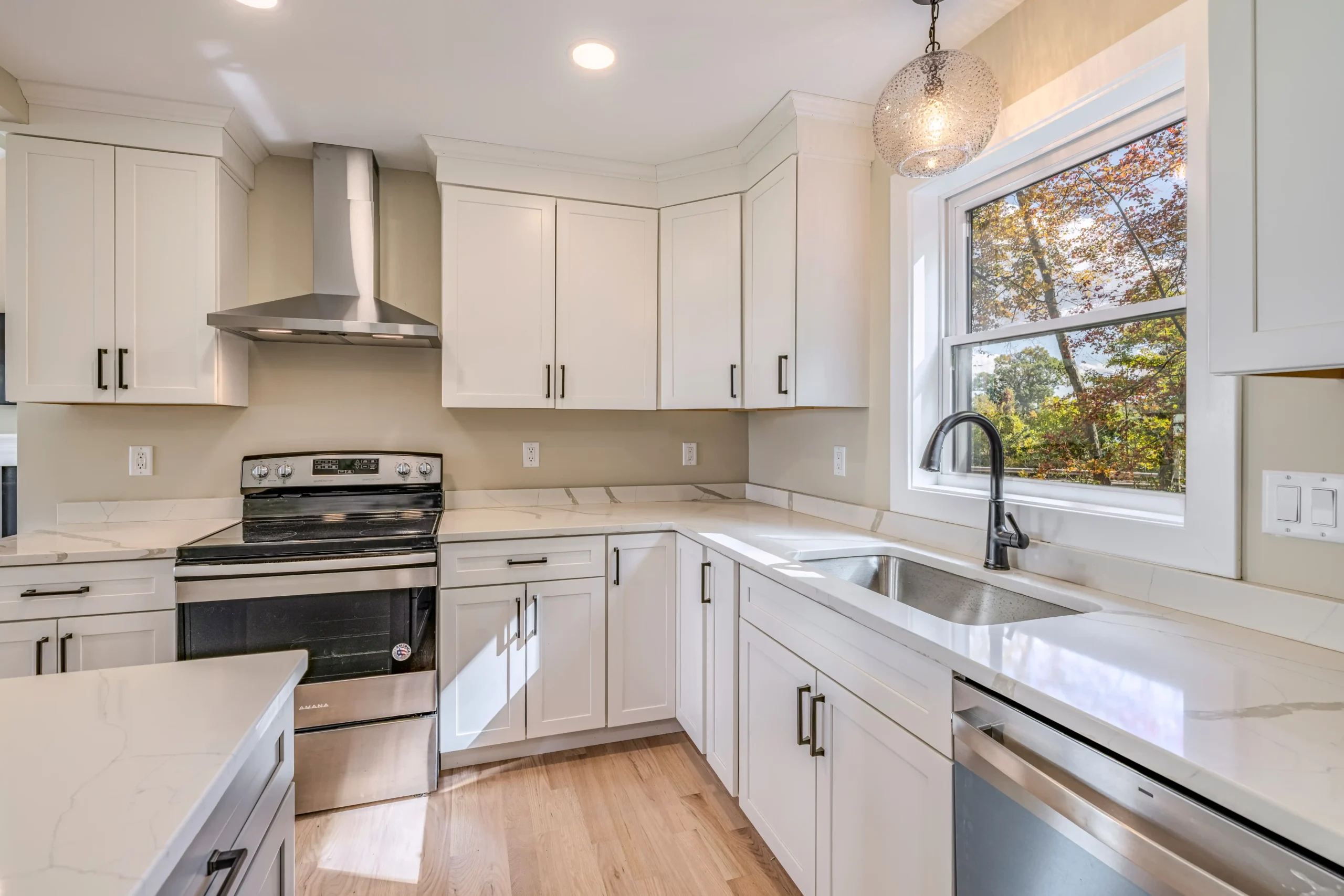 Crystal Lake Home 5 Elm Street Modern white kitchen with stainless steel range hood, white cabinets and window above sink