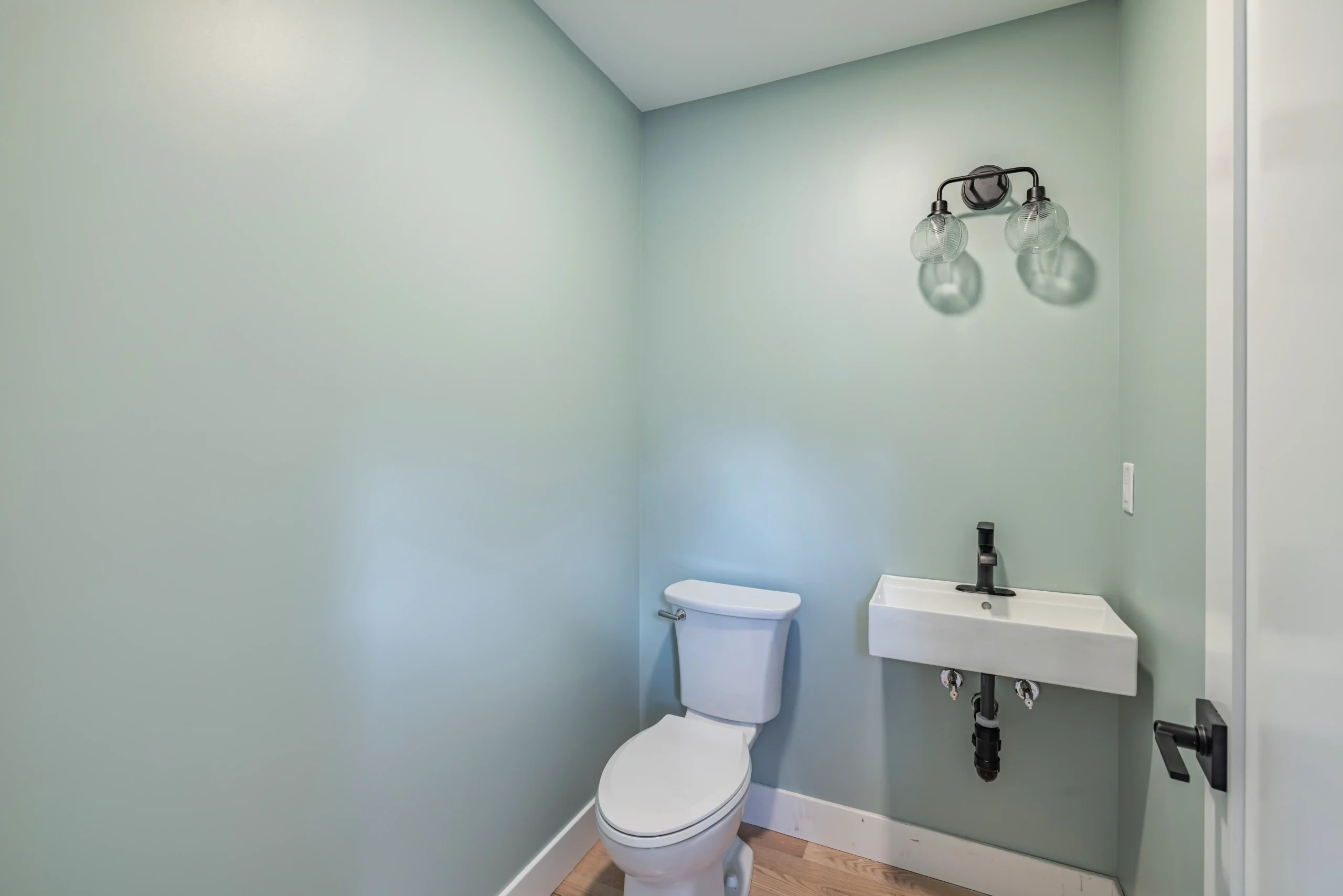 Crystal Lake Home 5 Elm Street Bathroom vanity with pale blue-green walls, white countertop and decorative wall lighting