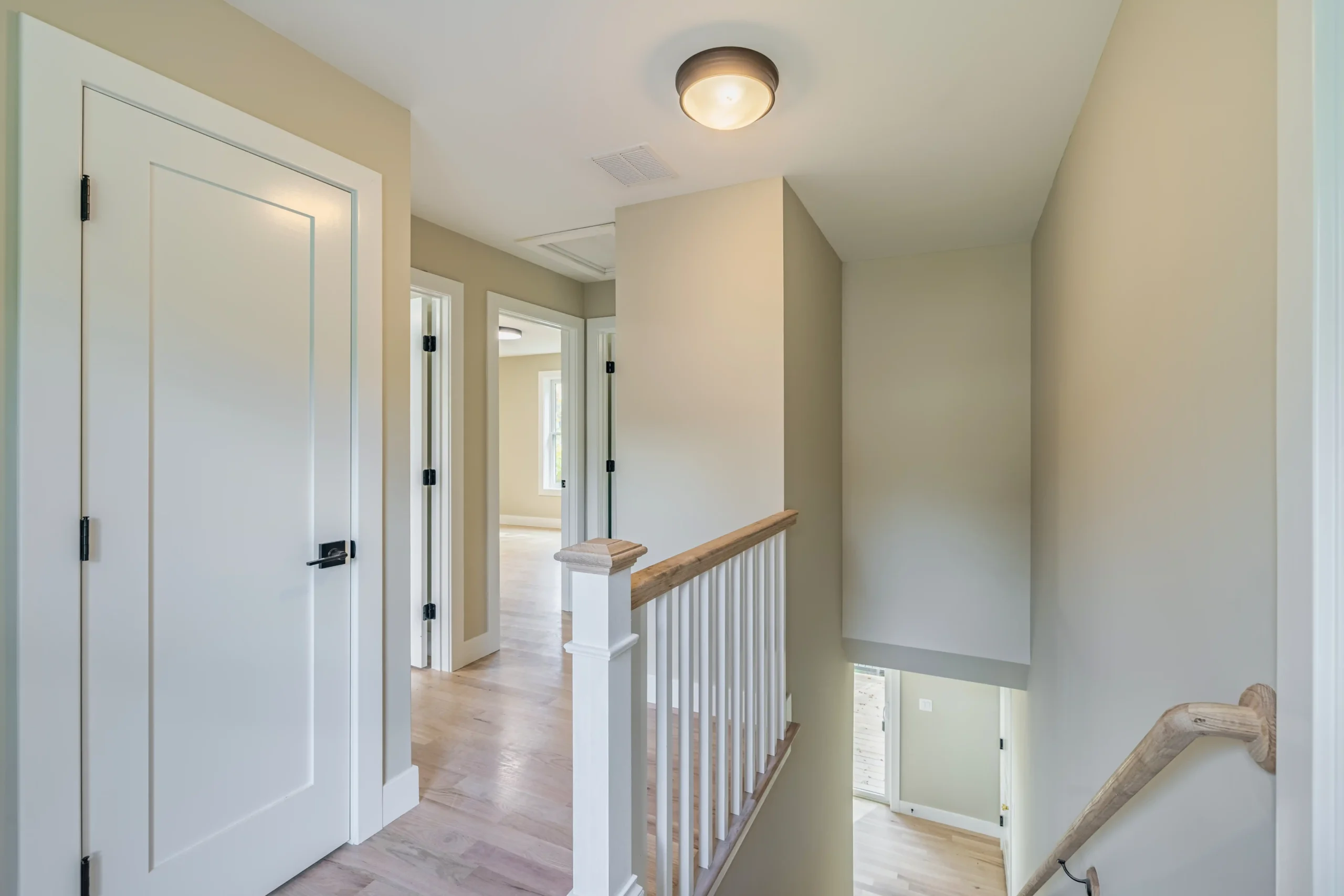 Crystal Lake Home 5 Elm Street Upstairs hallway with wooden stair railing, white doors and ceiling light