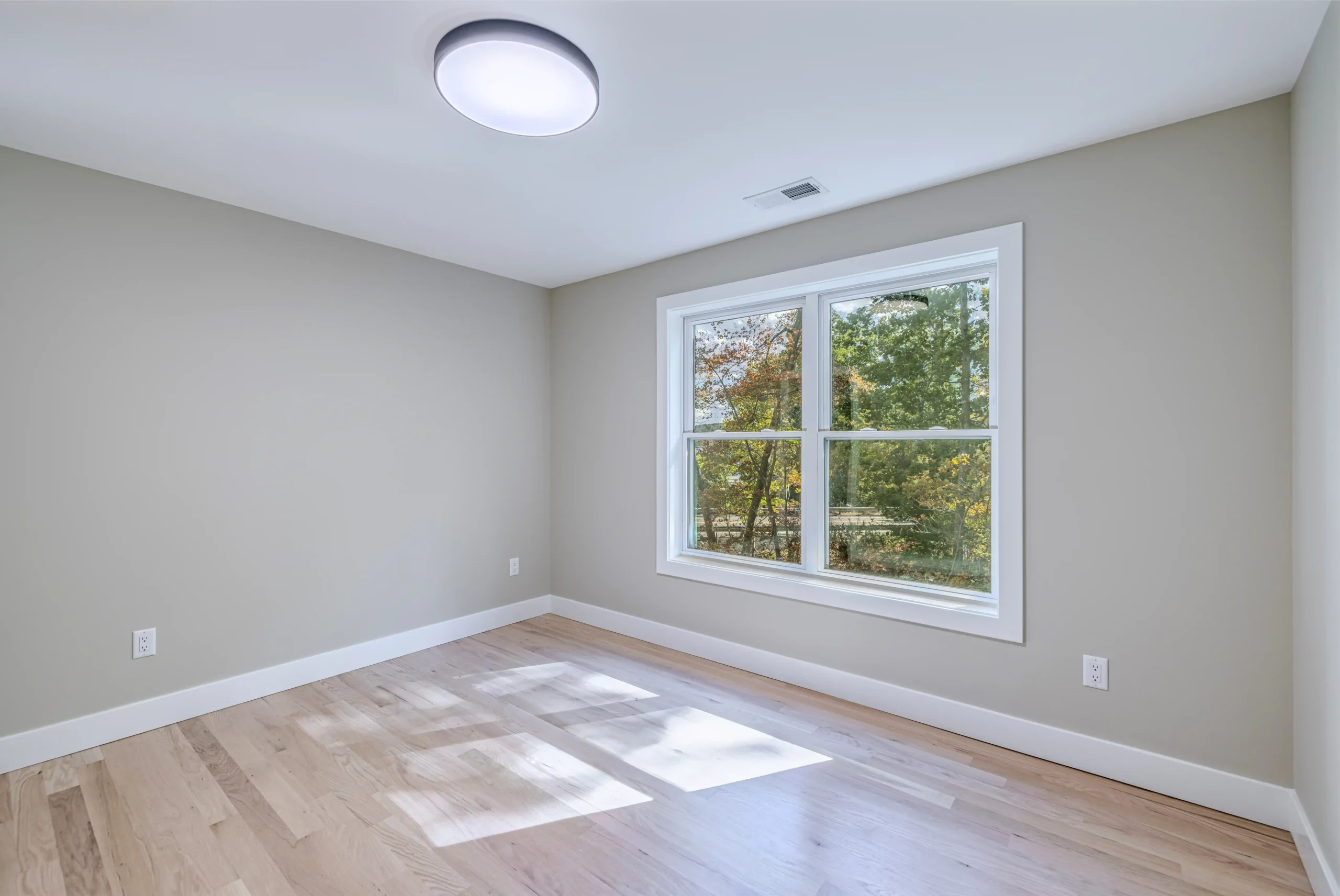 Crystal Lake Home 5 Elm Street Bright bedroom with neutral walls, ceiling light and large window overlooking trees