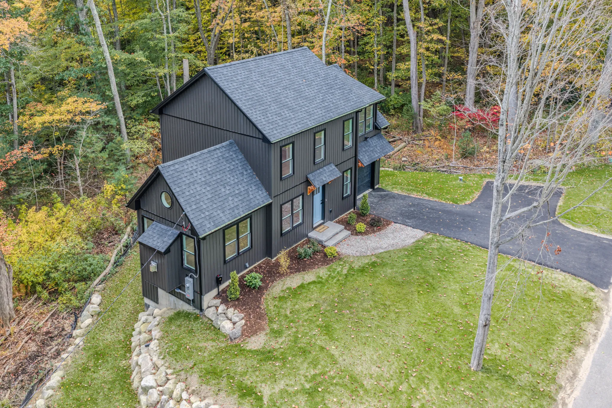 Crystal Lake Home 5 Elm Street Aerial view of dark gray two-story home with driveway and wooded surroundings
