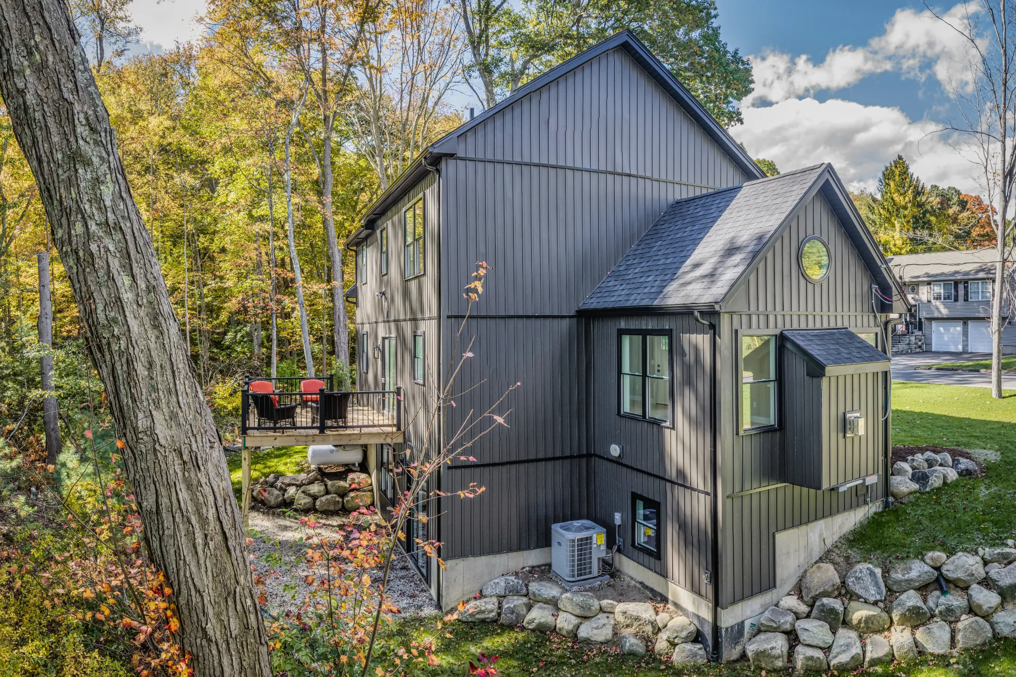 Crystal Lake Home 5 Elm Street Angled exterior view of modern dark gray home with gabled roof and wooded surroundings