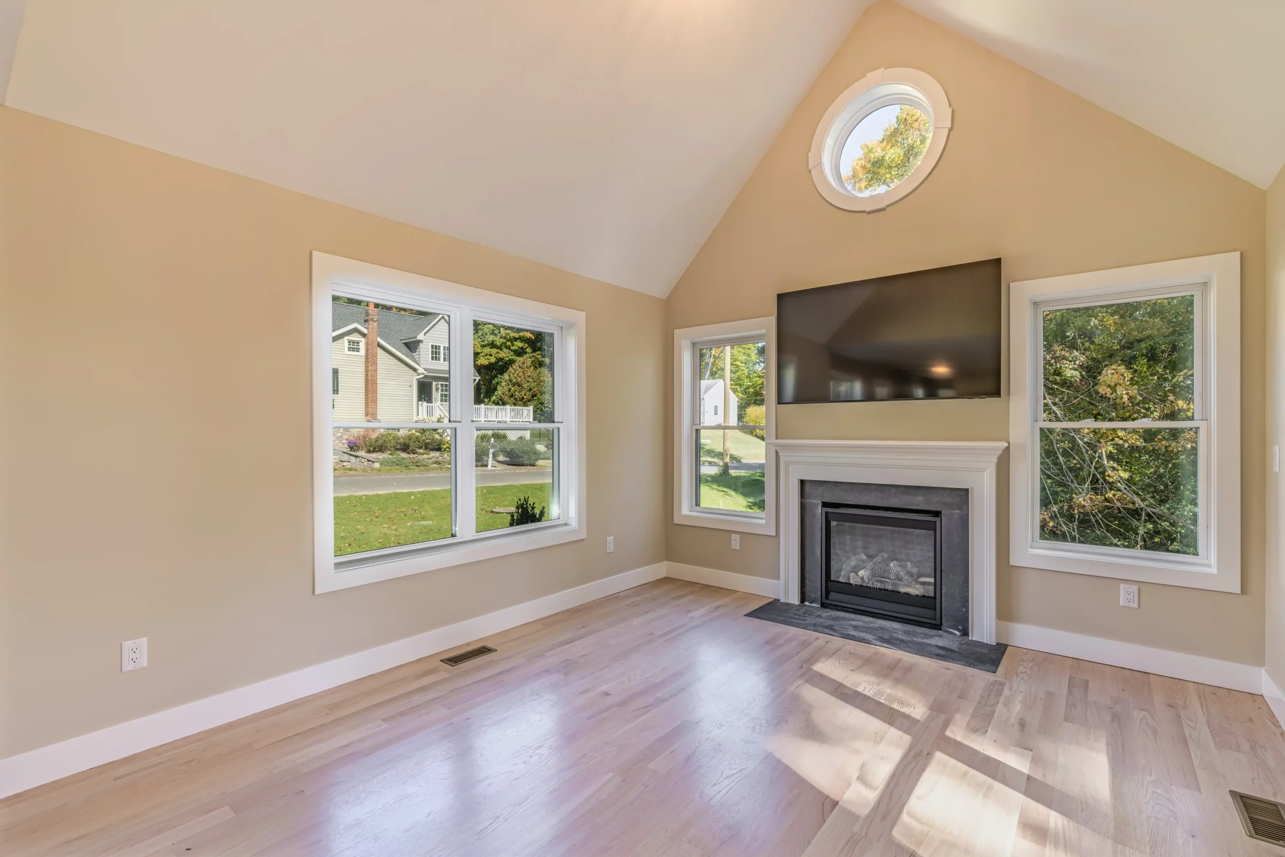 Crystal Lake Home 5 Elm Street Bright Vaulted living room with gas fireplace, mounted television and circular accent window