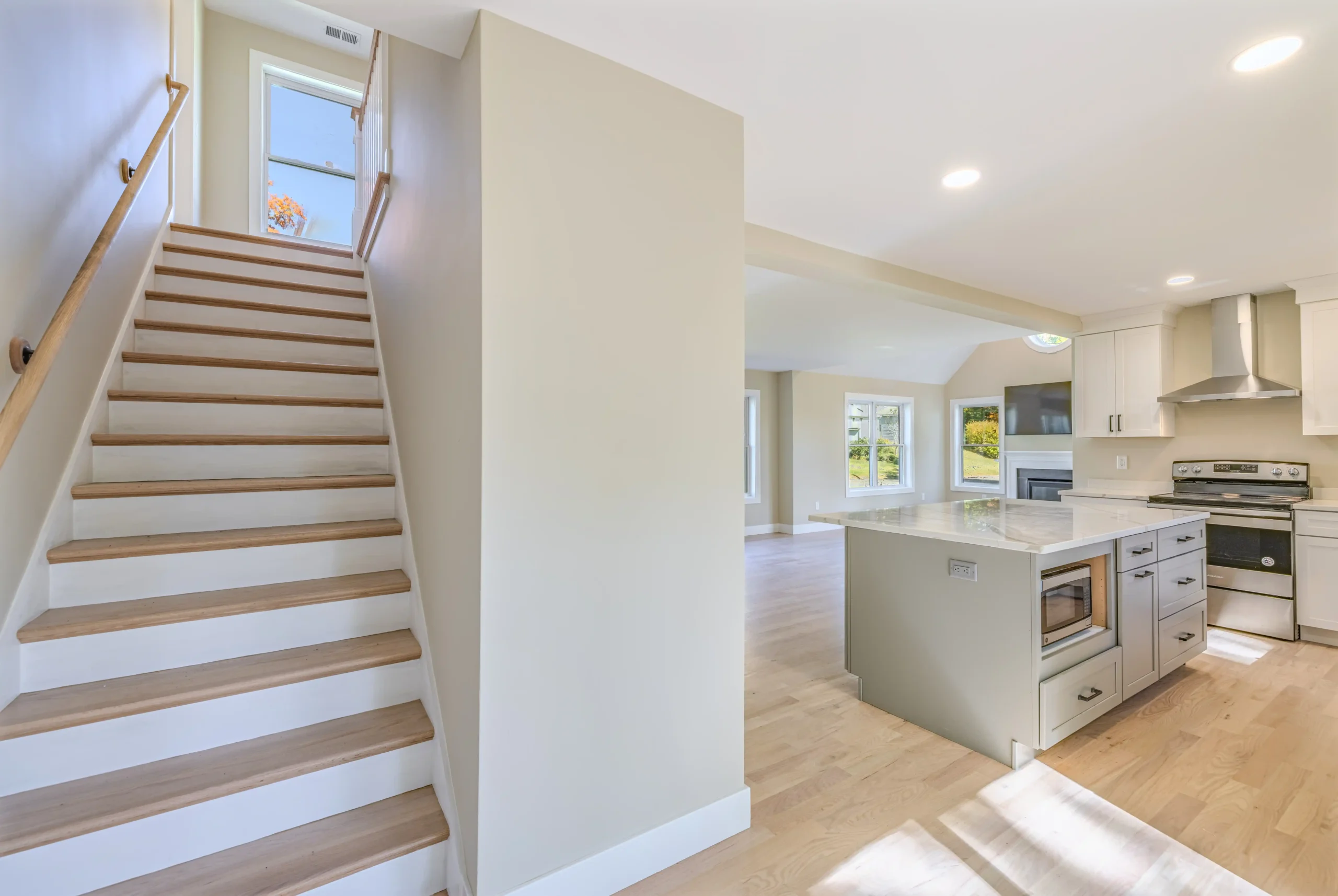Crystal Lake Home 5 Elm Street Open living area with staircase, seating and modern white kitchen in the background