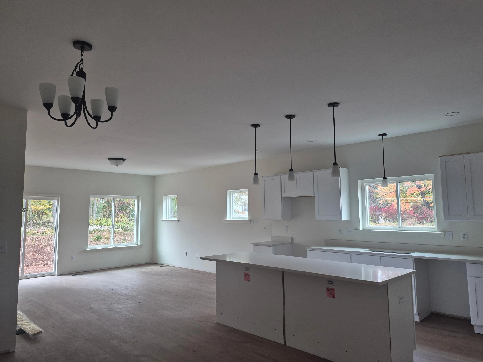 Edith Lane Beverly Farmhouse - Open-concept kitchen and living area with white cabinetry, pendant lights and large windows