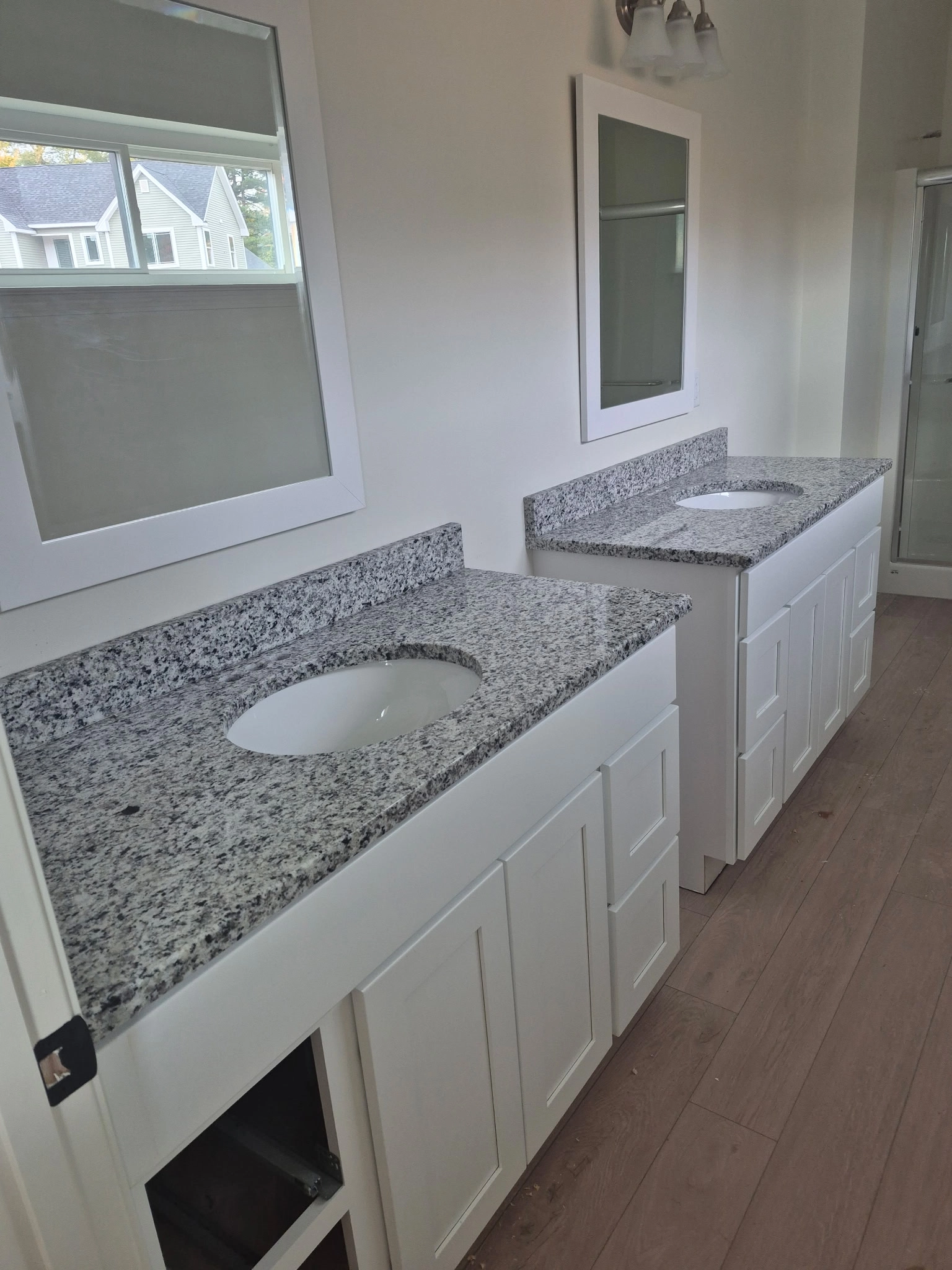 Edith Lane Beverly Farmhouse - Bathroom with two white sink vanities, granite countertops and large windows