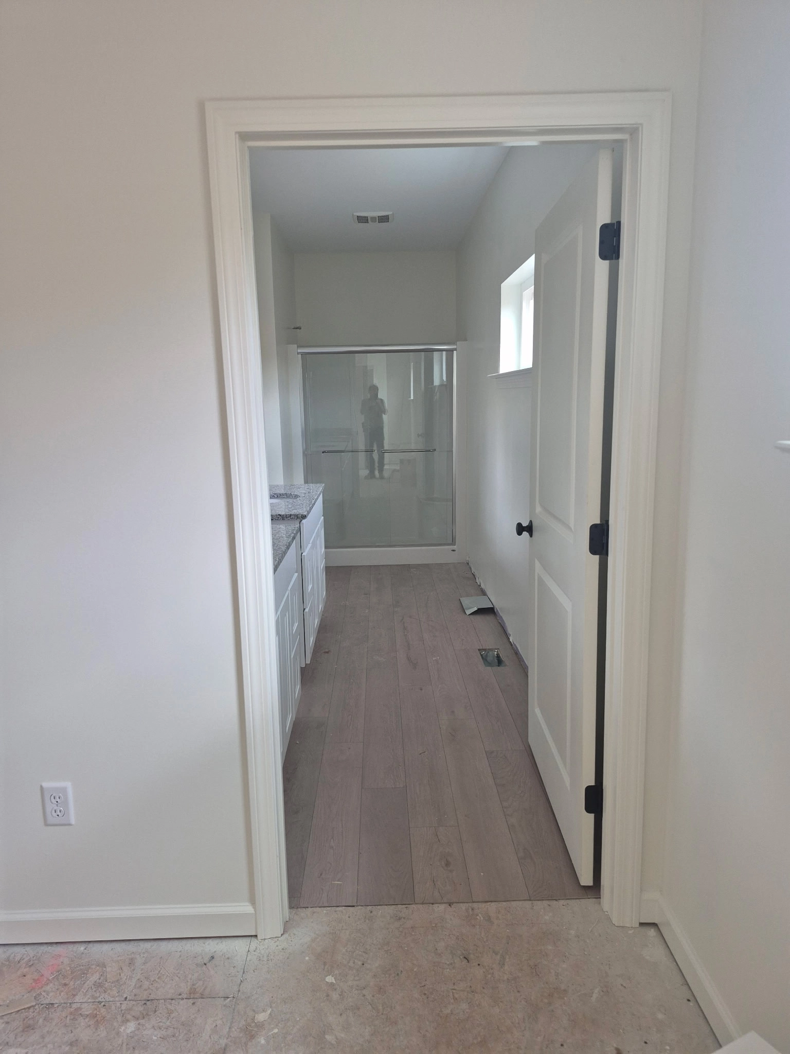 Edith Lane Beverly Farmhouse - Bright hallway with white interior doors leading toward a bathroom