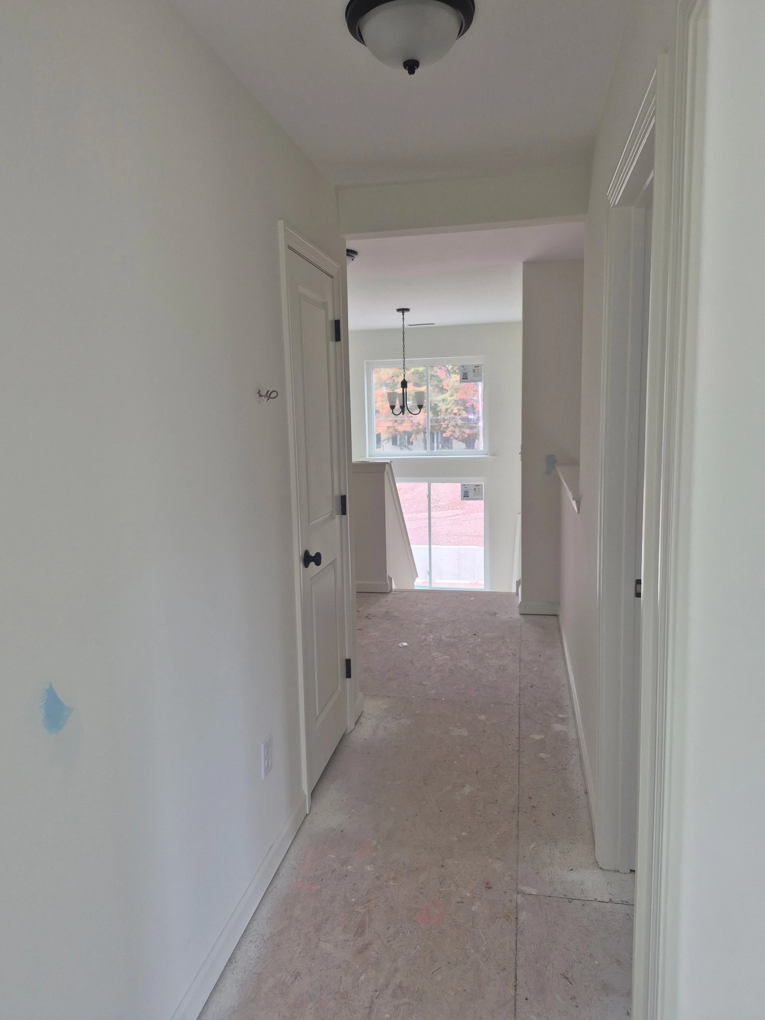 Edith Lane Beverly Farmhouse - White interior hallway with multiple doors and natural light from a window
