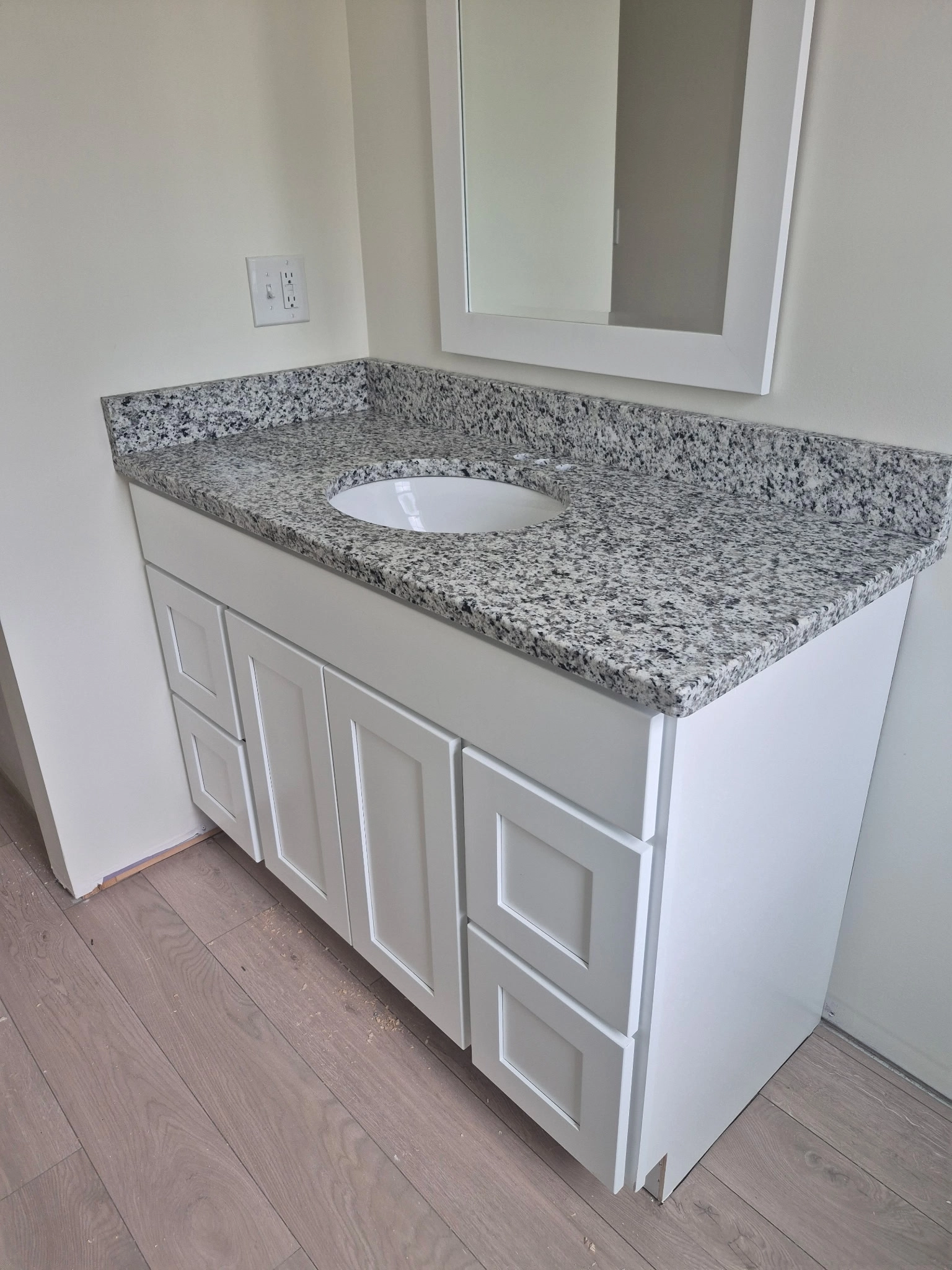 Edith Lane Beverly Farmhouse - Bathroom vanity with white cabinets, speckled granite countertop and undermount sink