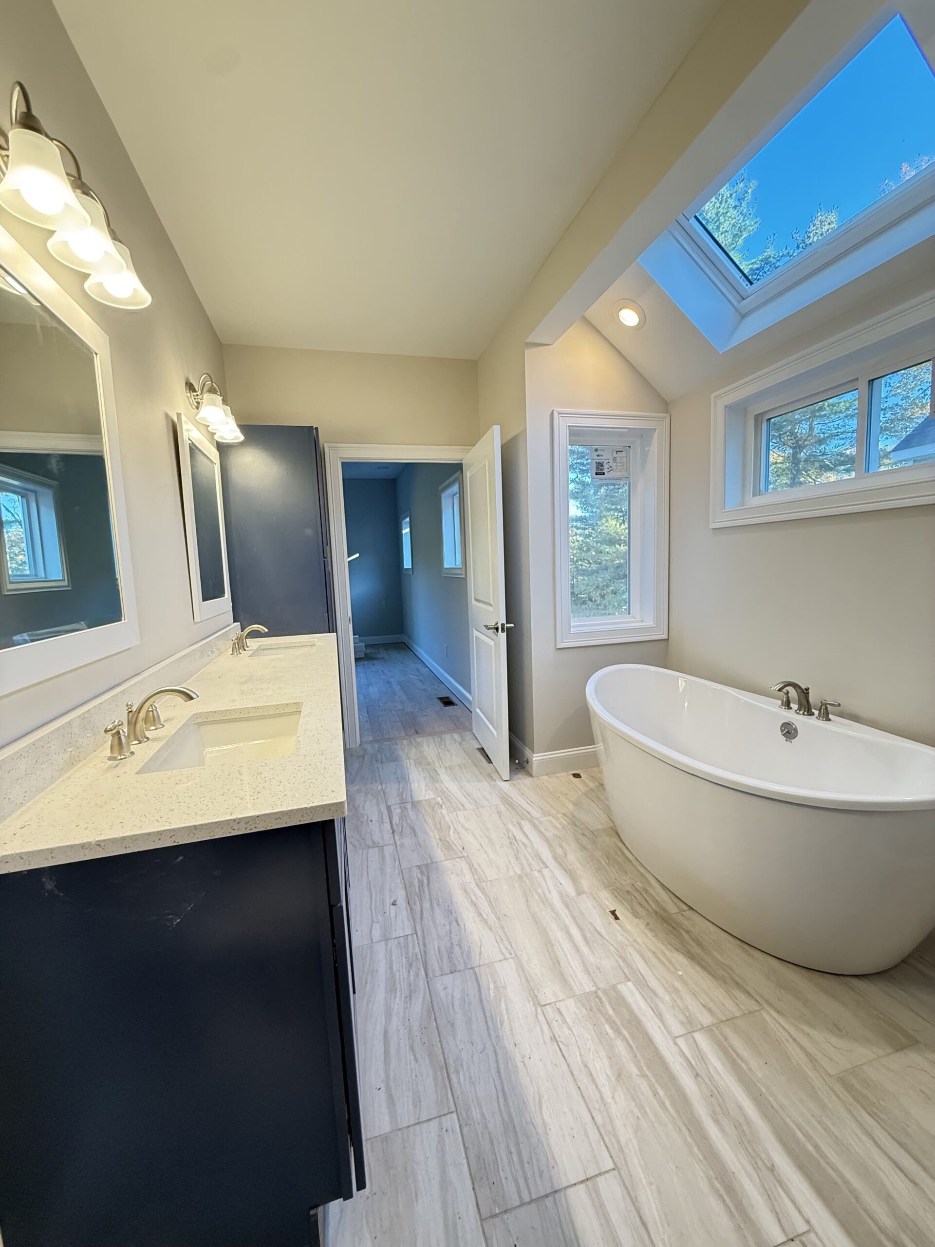 Modern bathroom with freestanding soaking tub, skylight, double vanity and large windows